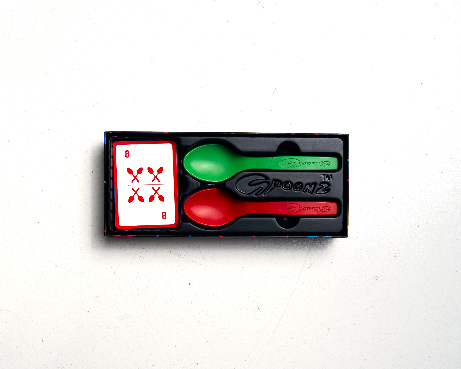 Spoonz box opened — cards and colored spoons in the tray, overhead view